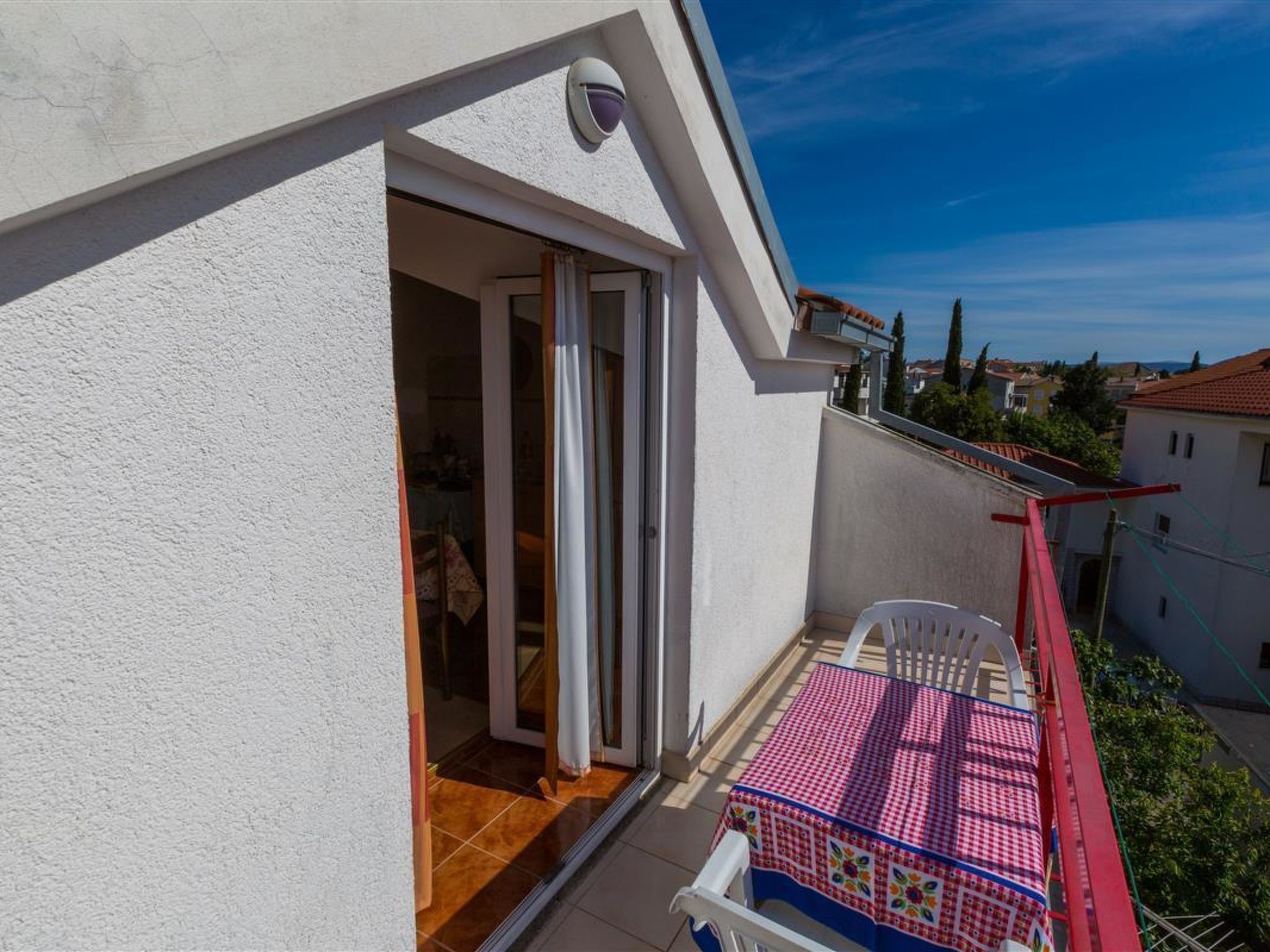Un balcon avec une table et des chaises, une porte coulissante et une vue sur le quartier.