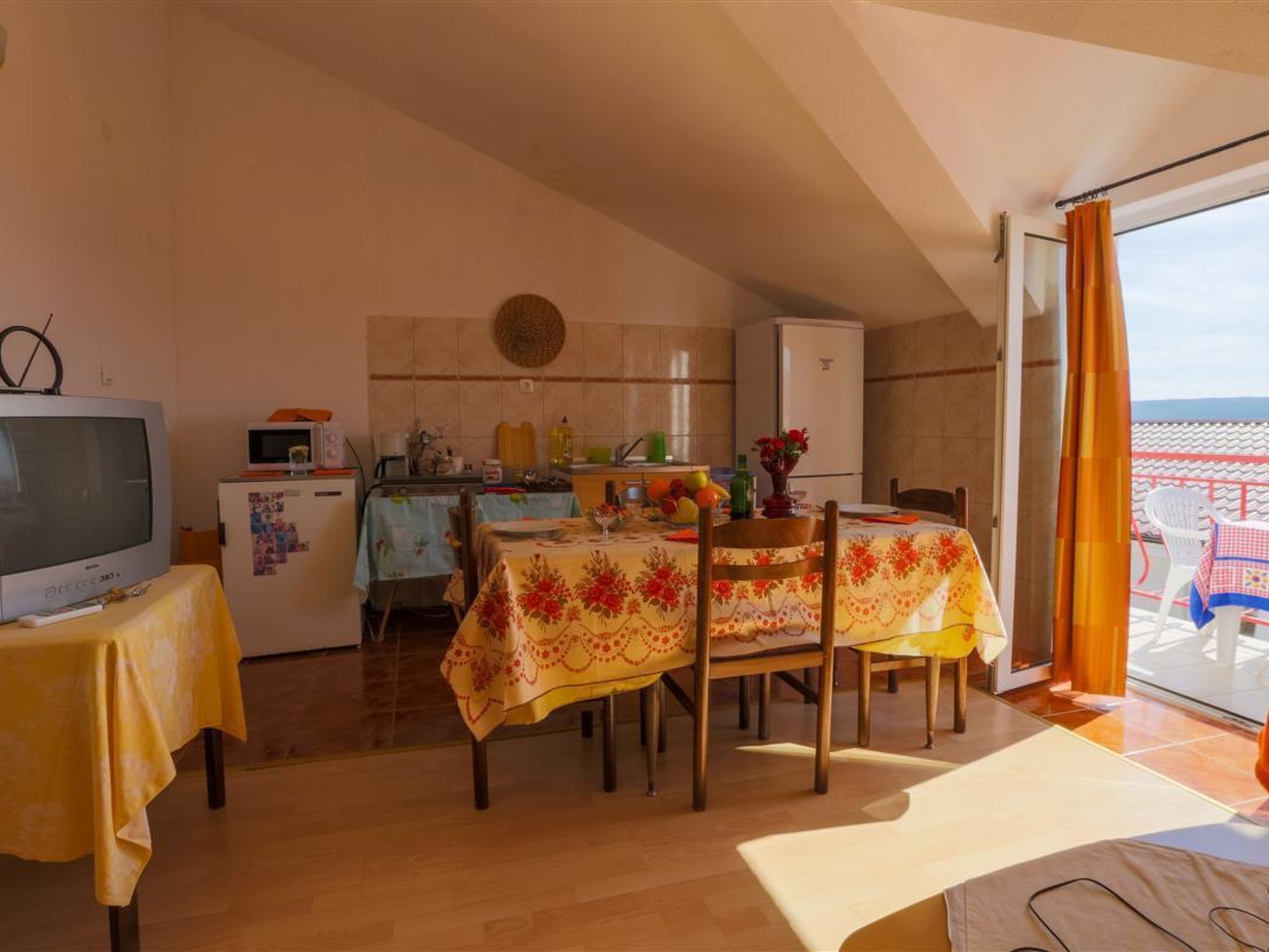 A compact kitchen with a refrigerator, microwave, and a dining area with a table set for two.