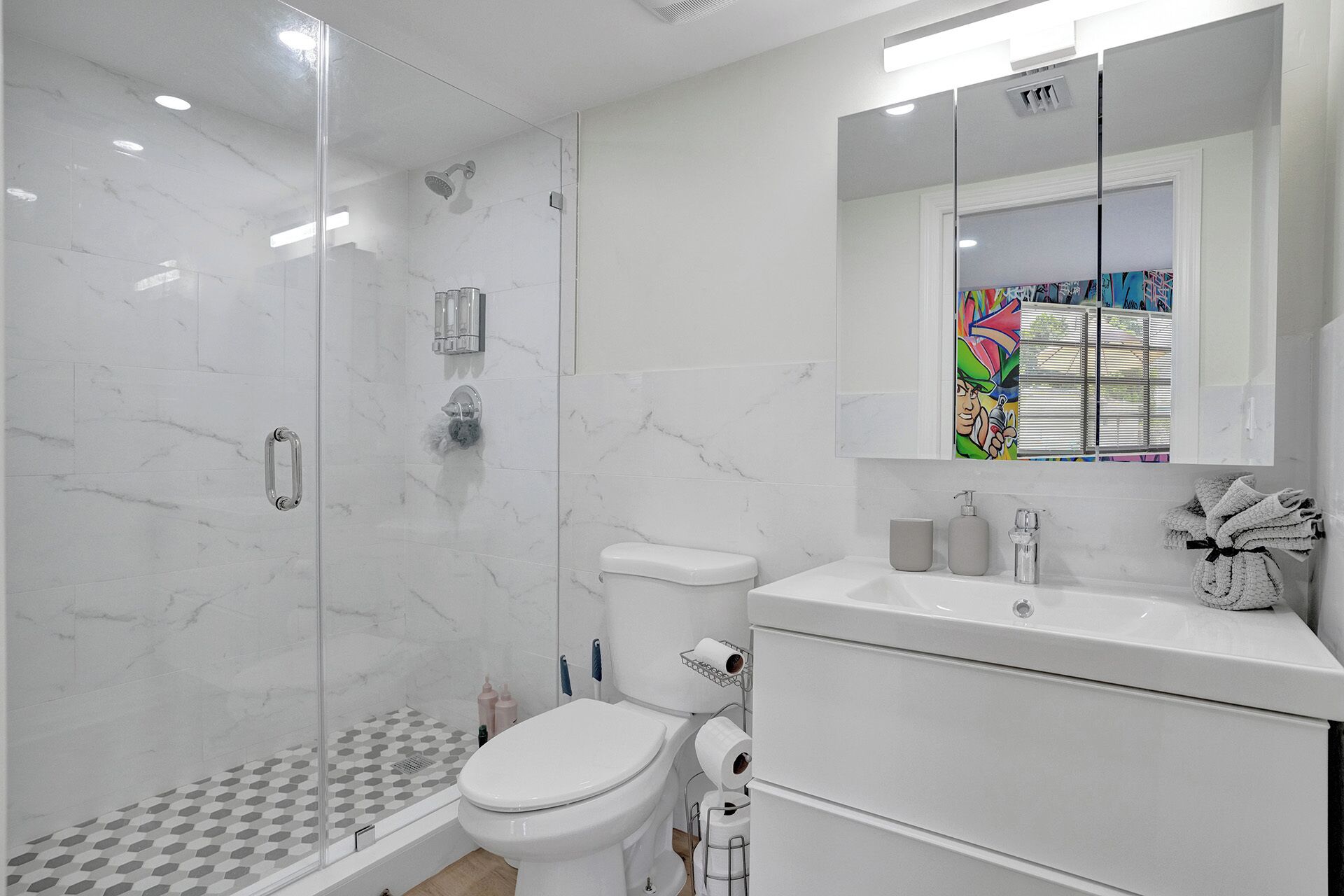 Een moderne badkamer met een douchecabine van glas, een toilet en een wastafel met een spiegel erboven.