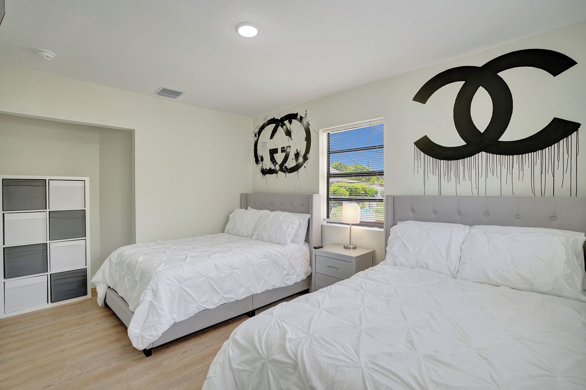 Un dormitorio con dos camas, un armario y una decoración grande en la pared.