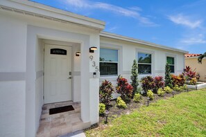 A residential building with a white exterior, a front door, and a small entryway. - MiamiMuralHouse:4BRw/Themes, Gameroom, Backyard (Miami)