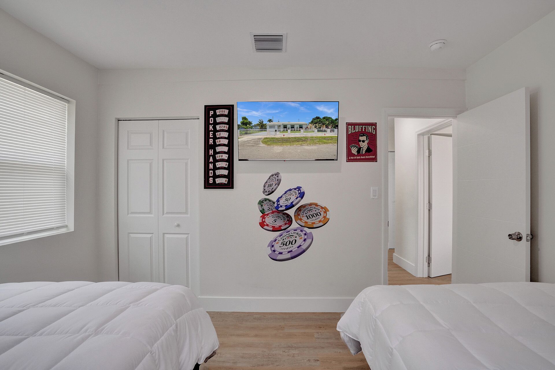 Habitación de hotel con dos camas, una puerta y adornos en la pared, incluyendo fichas de póker y una fotografía de un casino.