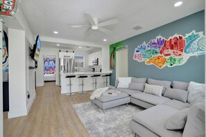 Ein modernes Wohnzimmer mit einem grauen Sofa, einem Couchtisch und einem farbenfrohen Wandbild.