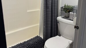 Ein Badezimmer mit Dusche, Toilette und einer kleinen Pflanze auf dem Toilettenbecken.