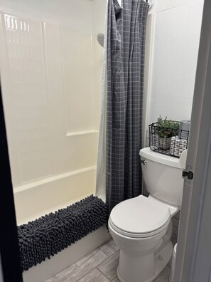 Ein Badezimmer mit Dusche, Toilette und einer kleinen Pflanze auf dem Toilettenbecken.