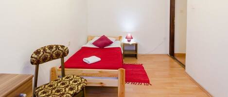 A small room with a bed, a chair, a nightstand, and a lamp.
