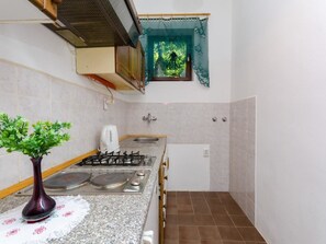 Uma cozinha compacta com fogão a gás, chaleira e uma pia pequena.