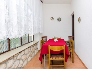 A dining area with a stone wall, a table with a red tablecloth, and four wooden chairs. - GOLIC Wine / HR-03619-03 by Interhome (Crikvenica/Dramalj)