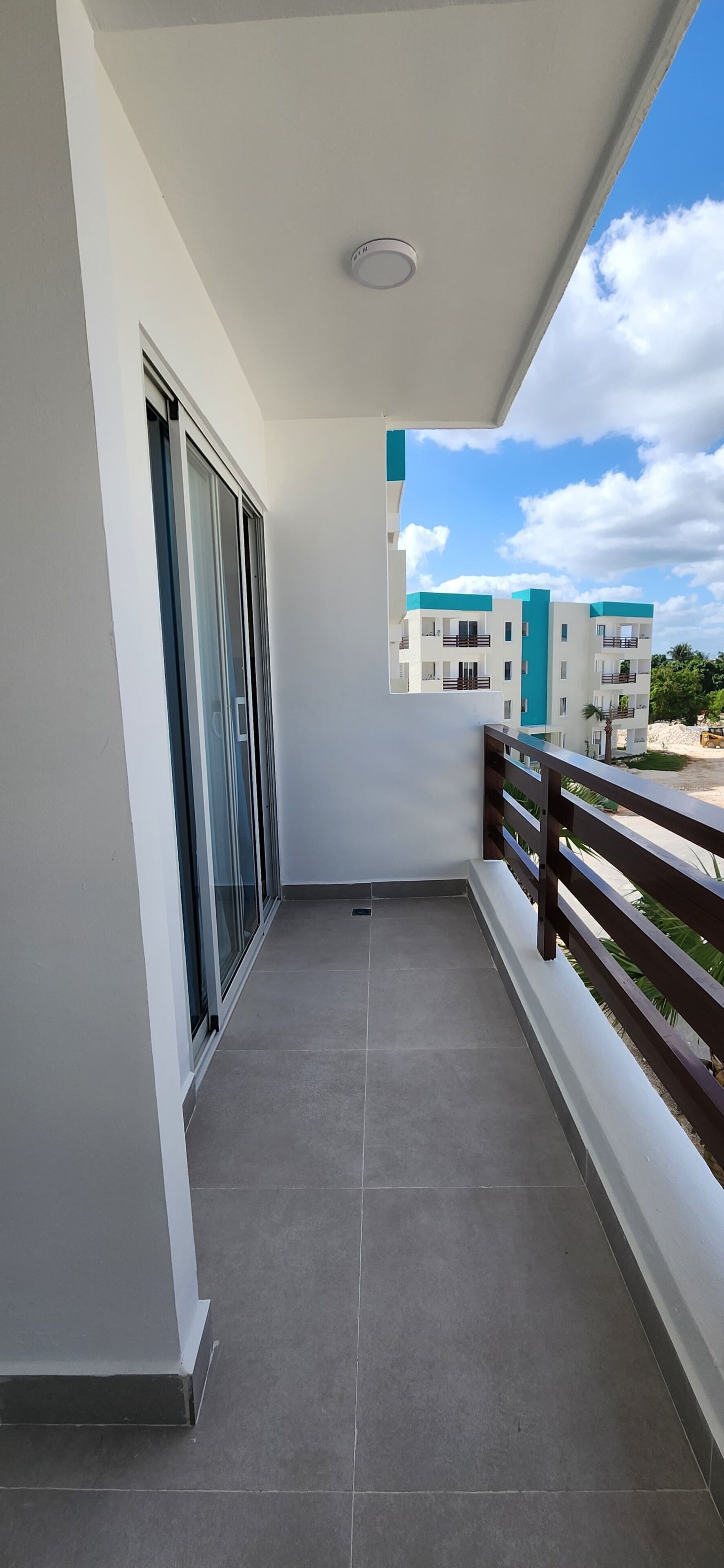 Un balcon donnant sur un immeuble et un ciel dégagé.