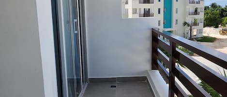 Un balcon donnant sur un immeuble et un ciel dégagé.