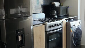 Een moderne keuken met een koelkast, fornuis, oven, magnetron en wasmachine.