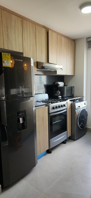 A modern kitchen with a refrigerator, stove, oven, microwave, and washing machine. - Amazing Suites 2-bedroom apartment with AC in Punta Cana (Punta Cana)