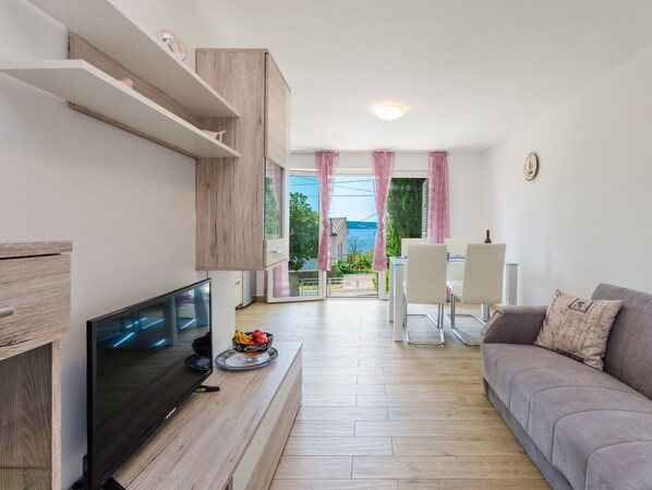 A modern living room with a flat-screen TV, a grey sofa, and a dining area with a table and chairs. - Leng 1 / HR-10352-01 by Interhome (Crikvenica/Dramalj)