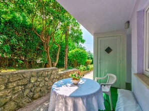 A small outdoor seating area with a table and chairs, surrounded by greenery and a stone wall. - Leng 1 / HR-10352-01 by Interhome (Crikvenica/Dramalj)