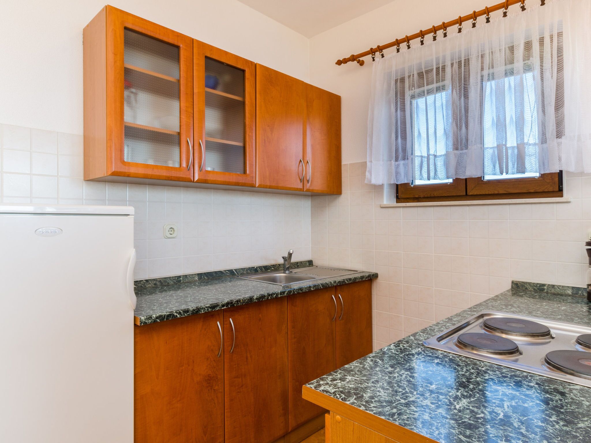 A kitchen with wooden cabinets, a stainless steel sink, and a stove.