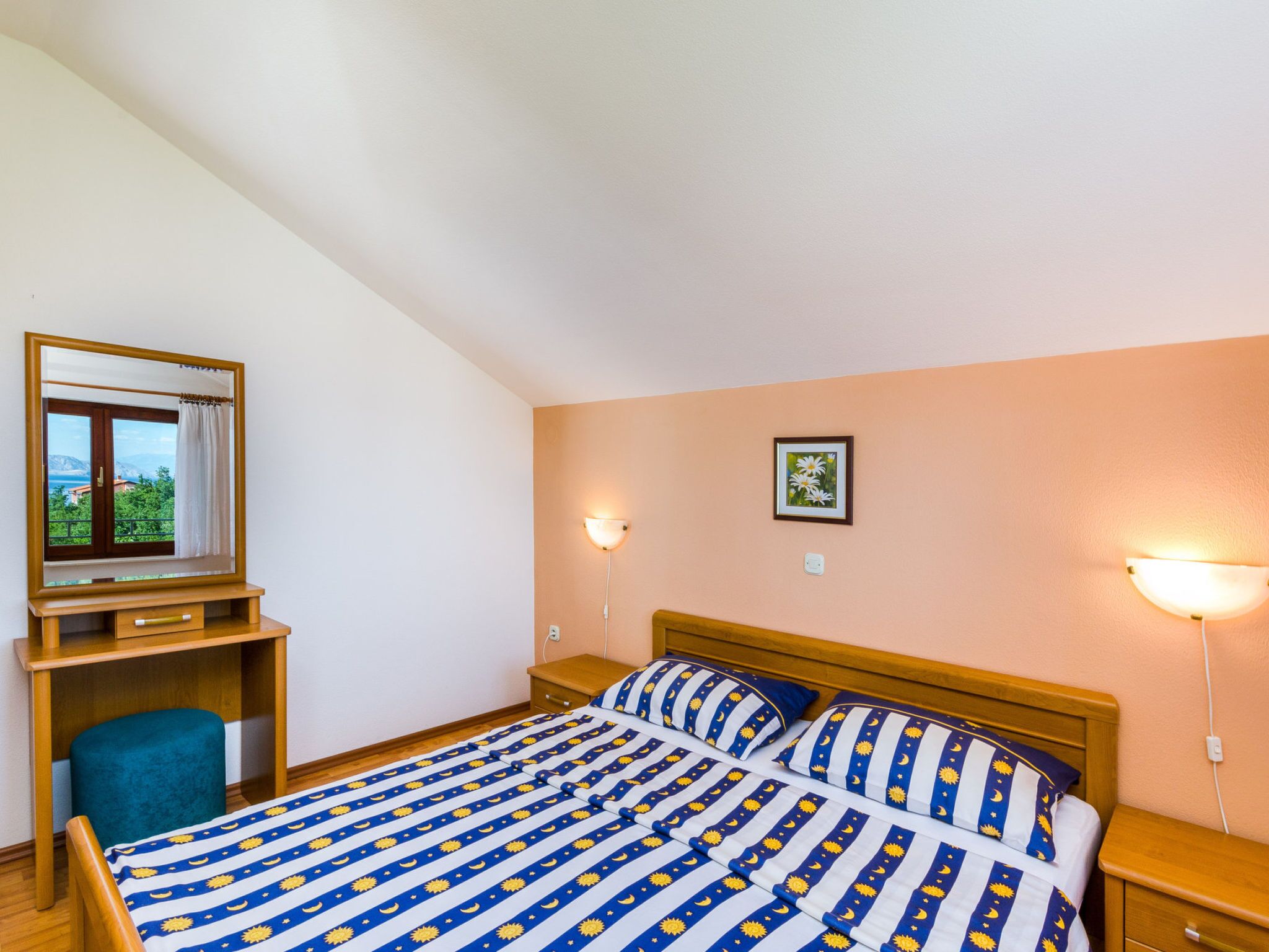A bedroom with a bed, a desk, a chair, and a window with a view.