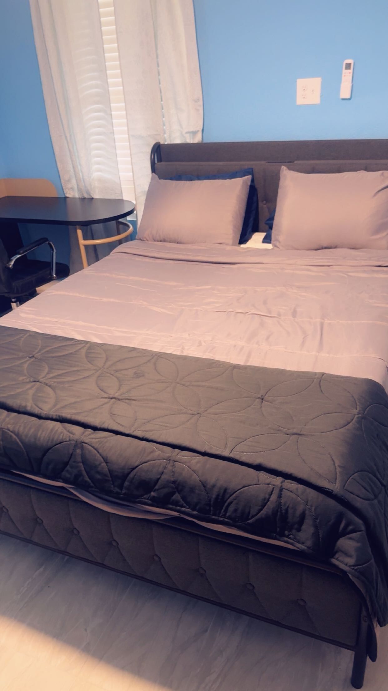 Ein Bett mit dunkel gestepptem Kopfteil, ein Nachttisch und ein Stuhl.