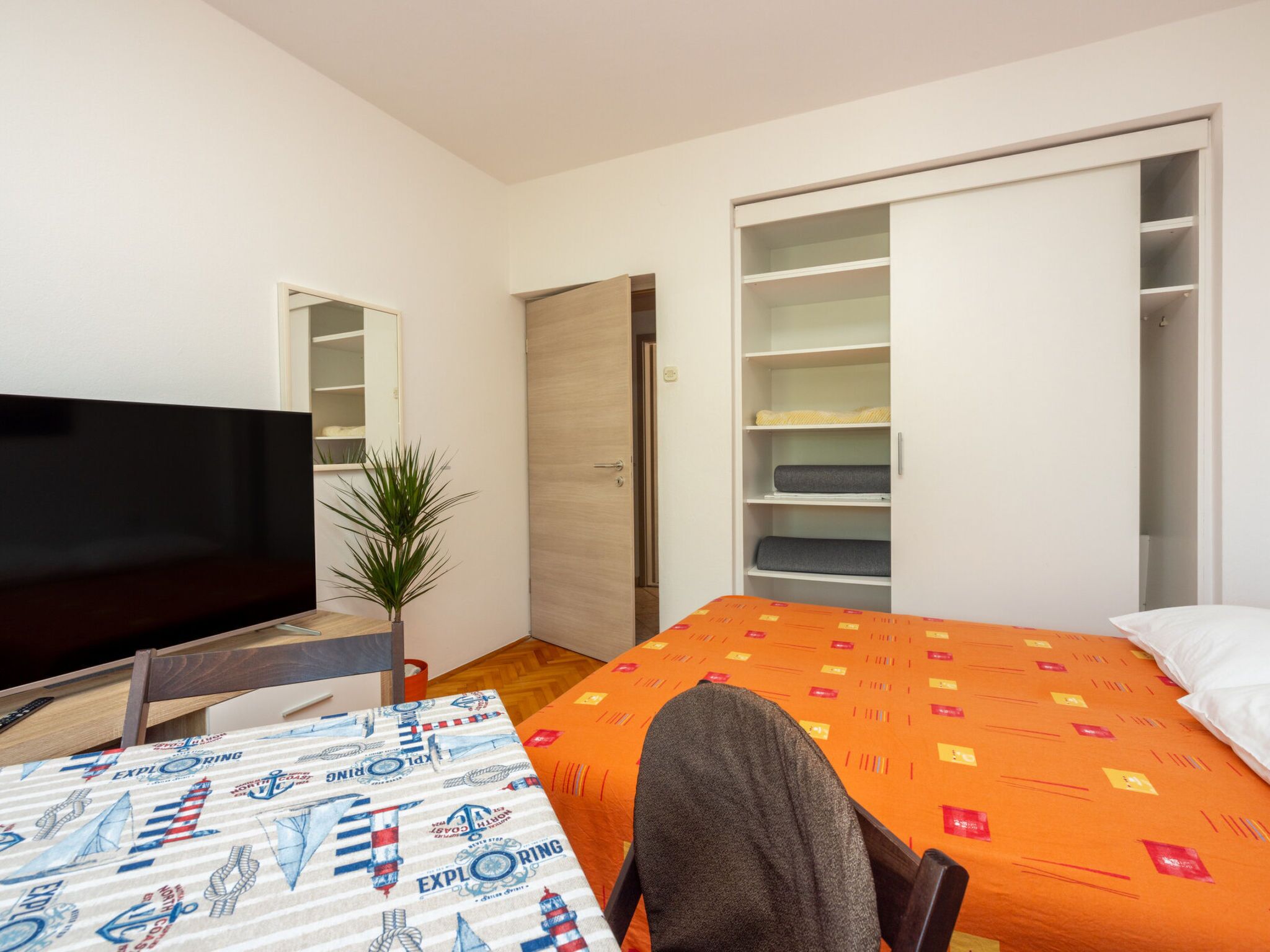 Een slaapkamer met een bed, een televisie, een bureau en een kledingkast.
