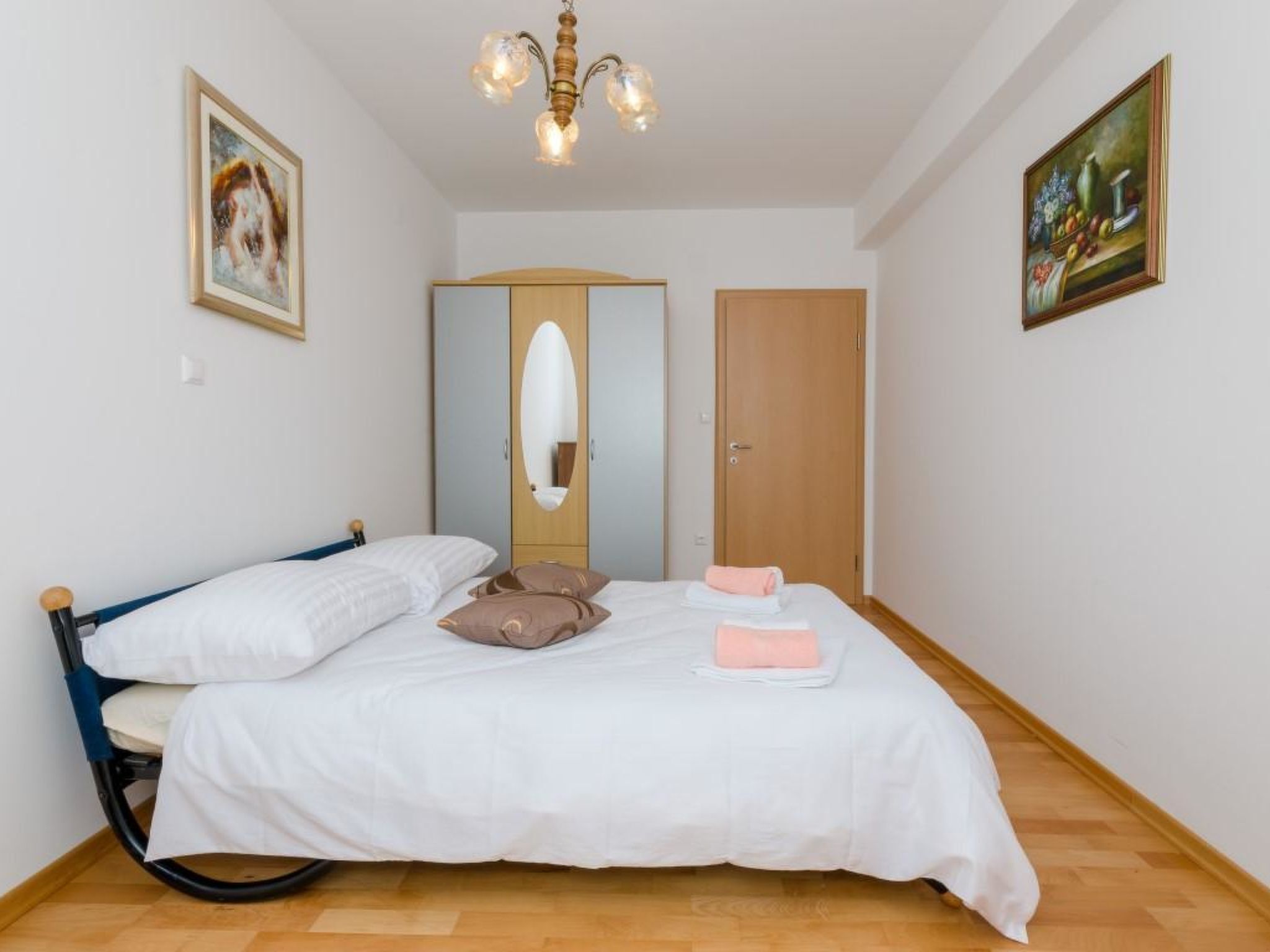 Un dormitorio con cama, armario, espejo y candelabro.