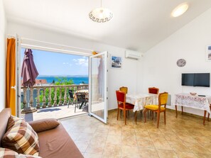 Een kamer met balkon, eethoek en televisie.