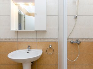 Ein Badezimmer mit Waschbecken, Spiegel, Dusche und dekorativen Fliesen.