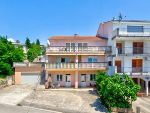 Ein mehrstöckiges Wohngebäude mit Balkonen, einer Garage und einer kleinen Terrasse.