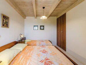 A bedroom with a wooden ceiling, a bed with patterned bedding, a nightstand with a lamp, and a wardrobe. - SARAR KOTOR CH / HR-10358-02 by Interhome (Crikvenica)