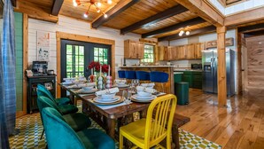Un interior de madera con una mesa de comedor para cuatro personas, una cocina con armarios de madera y un ventanal grande.