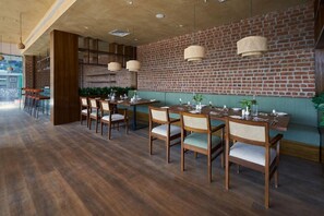 Un ristorante con tavoli e sedie di legno, pareti in mattoni e lampade a sospensione.