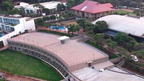 A large building with a curved roof, a swimming pool, and a parking area.