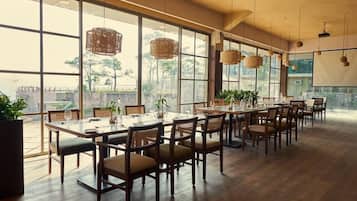 A spacious dining area with large windows, wooden tables, and chairs.