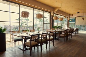 Un comedor espacioso con ventanas amplias, mesas y sillas de madera.
