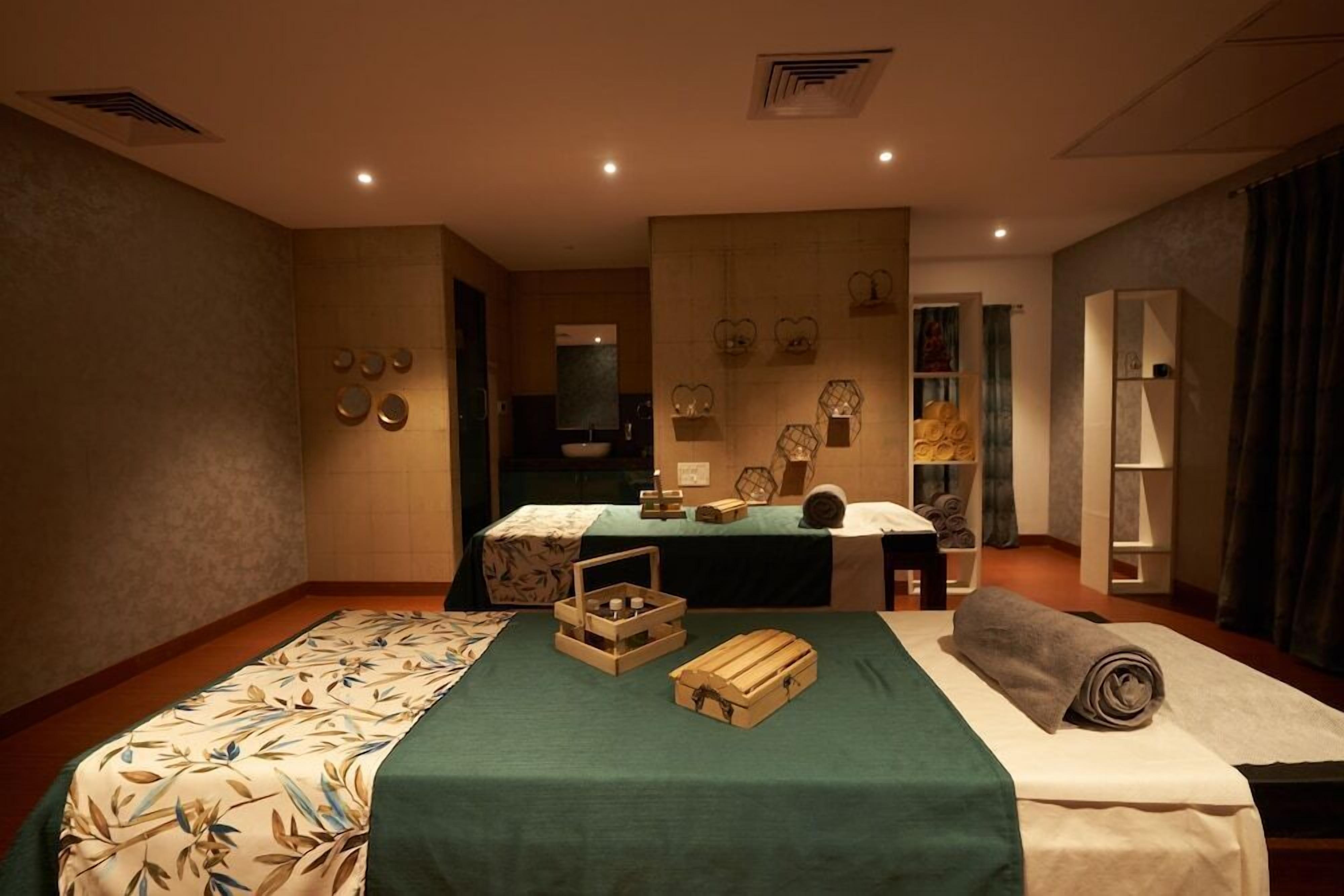 Habitación de hotel con cama, escritorio, espejo y estante con objetos decorativos.