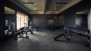 A gym with exercise equipment, mirrors, and a large window. - Ikshana Resort and Spa (Mawal)