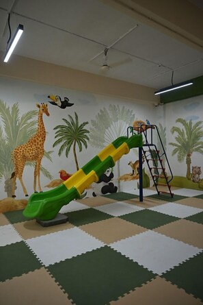 A play area with a slide, climbing structure, and wall murals of animals. - Ikshana Resort and Spa (Mawal)