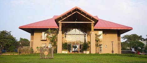 A building with a red roof, a glass entrance, and a well-maintained lawn.