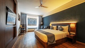 Habitación de hotel con una cama grande, lámparas de noche, un escritorio y vistas al exterior.