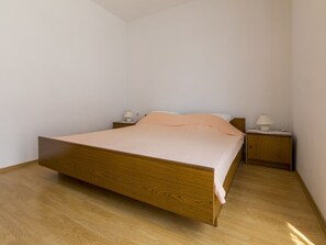 Ein Einzelbett mit Holzrahmen, zwei Nachttische mit Lampen und eine schlichte weiße Wand.