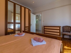 Hotellihuone, jossa on sänky, vaatekaappi, tuoli ja peili.