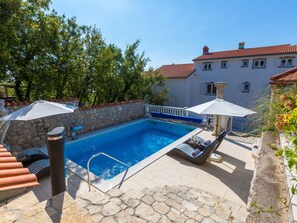 A swimming pool with stone walls, lounge chairs, and umbrellas. - BRANKA 1 / HR-02224-01 by Interhome (Crikvenica)