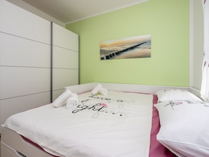 Ein Schlafzimmer mit Bett, Kissen, einem Wandbild und einer grünen Wand.