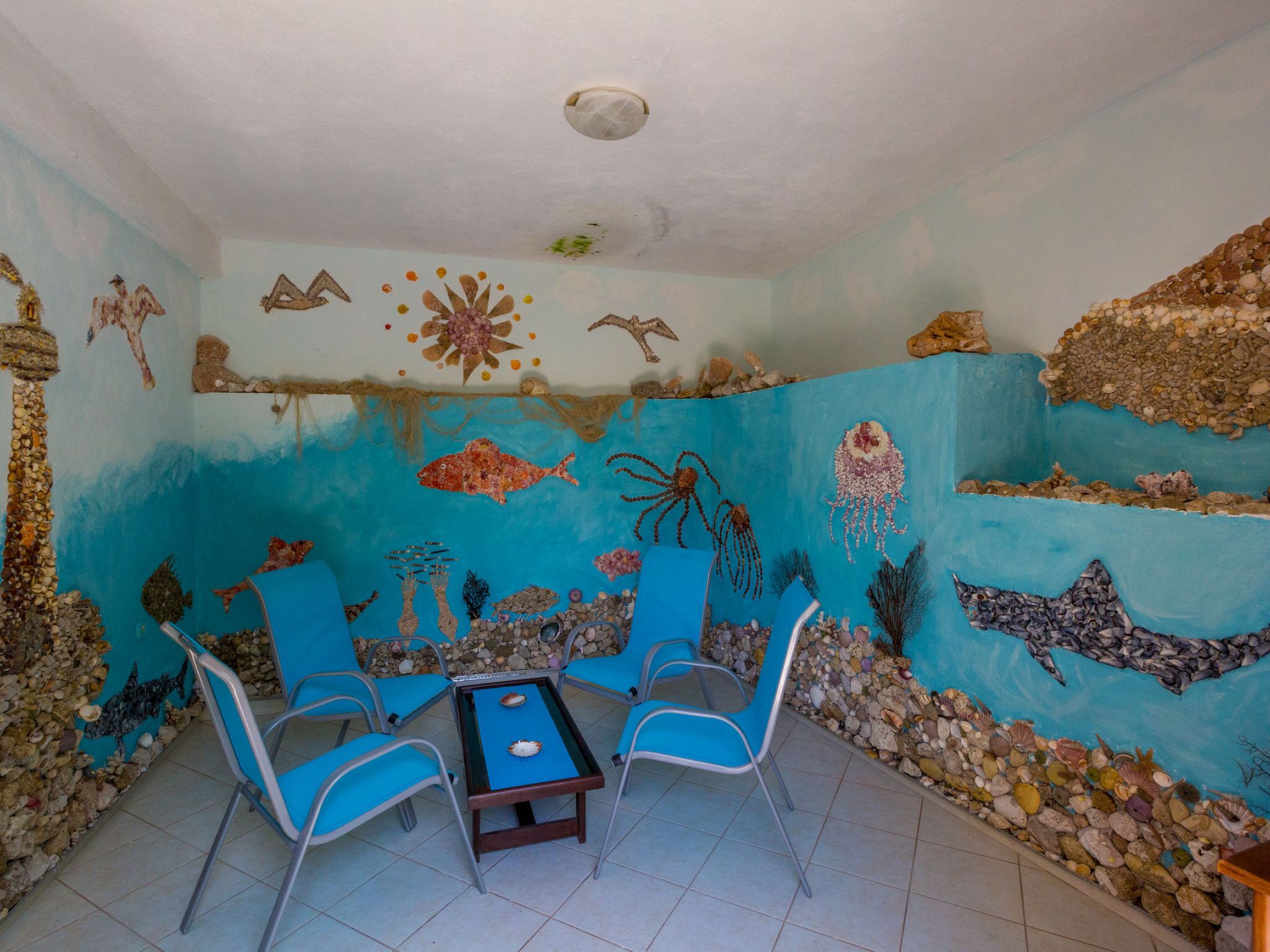 A room with a blue mural of marine life, a table with chairs, and a ceiling light.