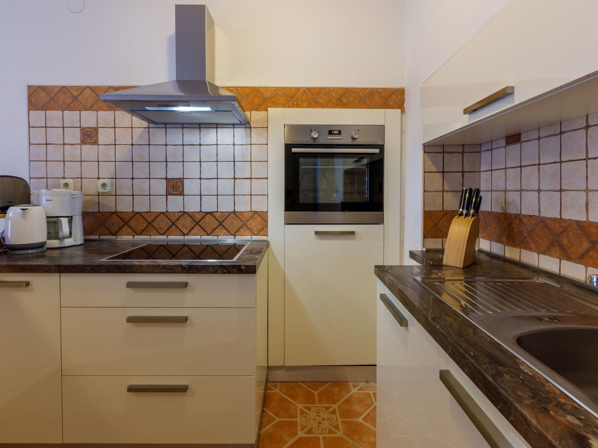 A kitchen with a built-in oven, a coffee maker, and a knife block.
