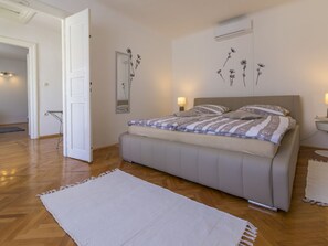 Een slaapkamer met een bed, nachtkastjes, een spiegel en een wandairconditioner.
