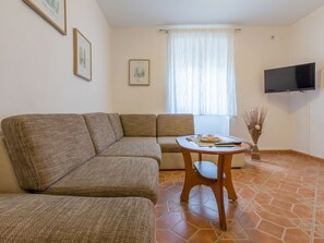 A living room with a sofa, a small table, a TV, and a window with curtains. - Haus Ivy / HR-08510-01 by Interhome (Crikvenica)