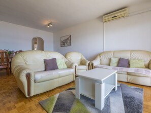 A living room with two beige sofas, a white coffee table, a patterned rug, and a wall-mounted air conditioner. - BUNETA 5 / HR-01926-07 by Interhome (Crikvenica)