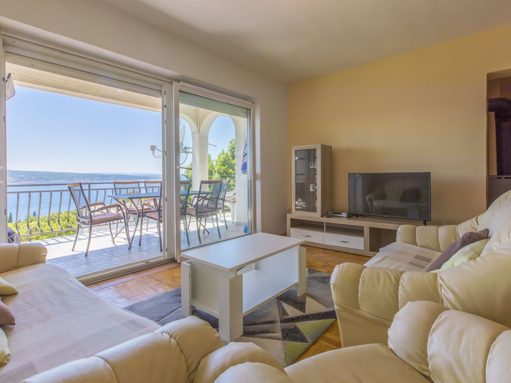 Un salon comprenant un canapé, un téléviseur, une table à manger et un balcon avec vue.