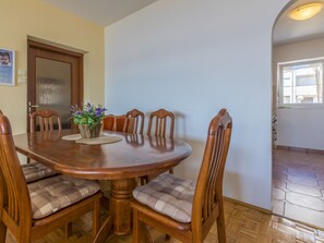 Un coin repas avec une table et des chaises en bois, un vase rempli de fleurs et une porte ornée d’un calendrier.