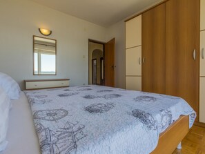 A bedroom with a bed, a bedside table, a wardrobe, and a mirror. - BUNETA 5 / HR-01926-07 by Interhome (Crikvenica)