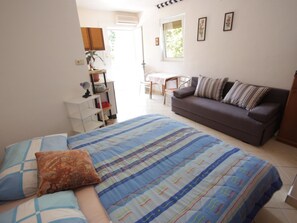 A bedroom with a bed, a sofa, a desk, and a chair. - KOSTRENCIC 3 / HR-09101-04 by Interhome (Crikvenica)